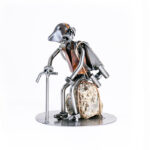 Vandrer metalfigur til naturelsker hviler på en sten, med kikkert, rygsæk og vandrestok. En gave til naturelsker, vandrer eller fuglekigger. Metalfigurer som gave webshop